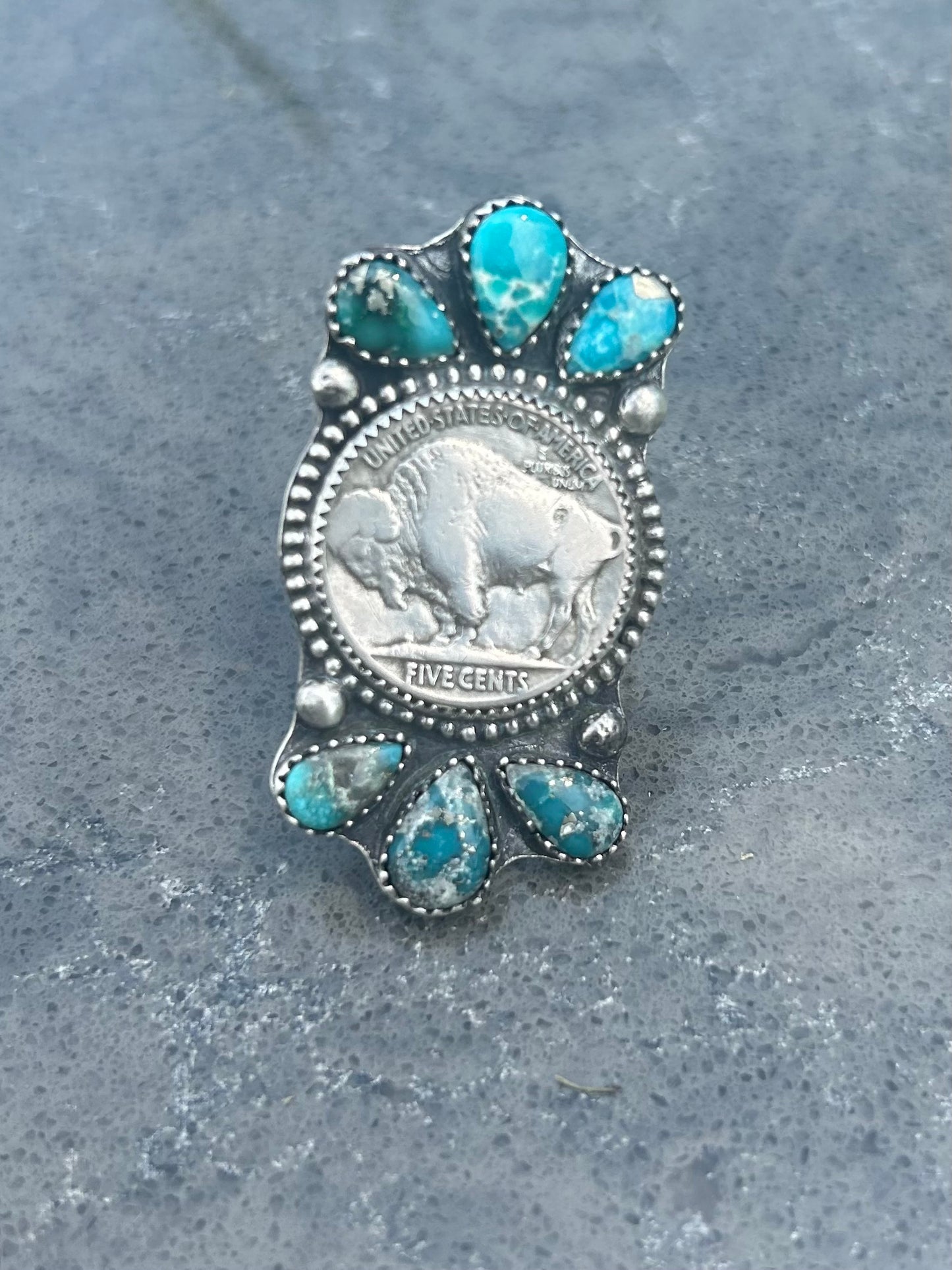 Silver ring with turquoise stones on a gray surface