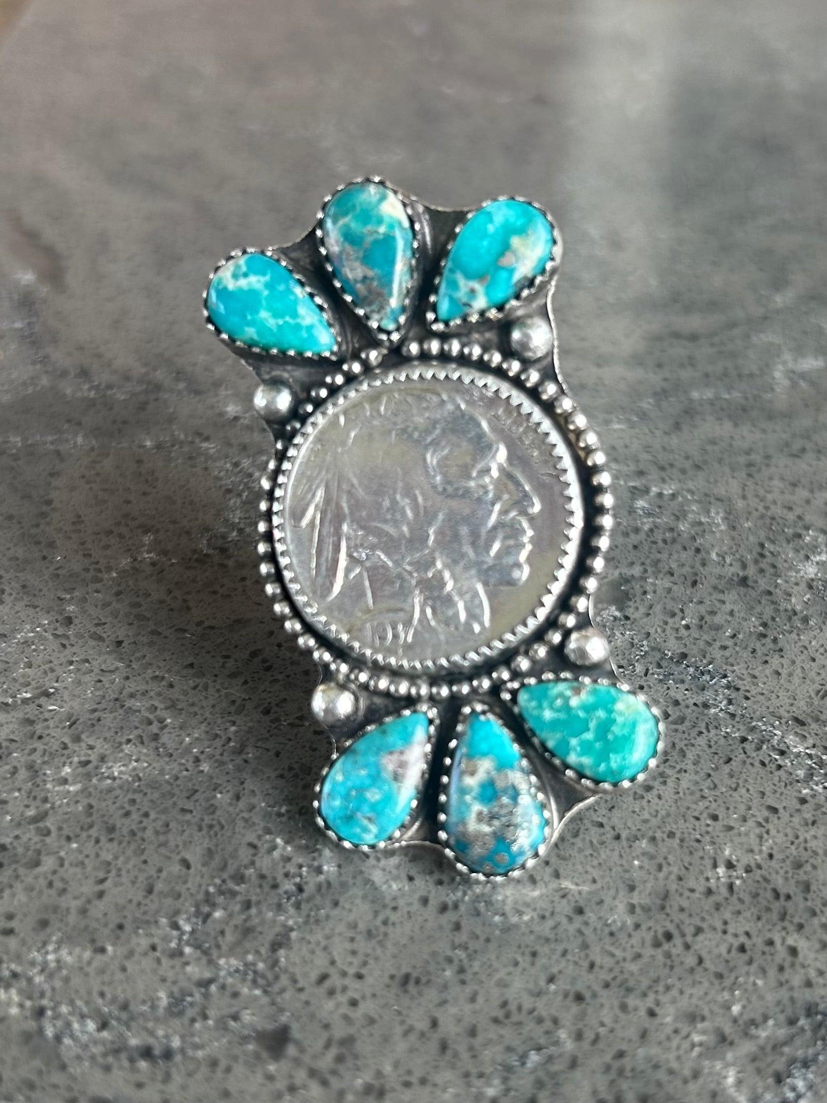 Silver ring with turquoise stones on a gray surface